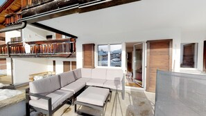 A modern outdoor living area with a sectional sofa, a dining table, and a pergola structure.
