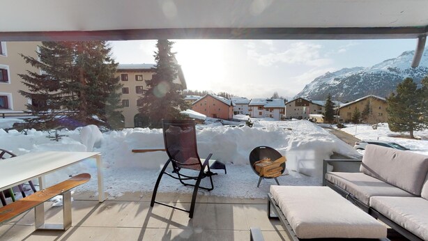 Un patio cubierto de nieve con un sofá, una silla y una mesa.