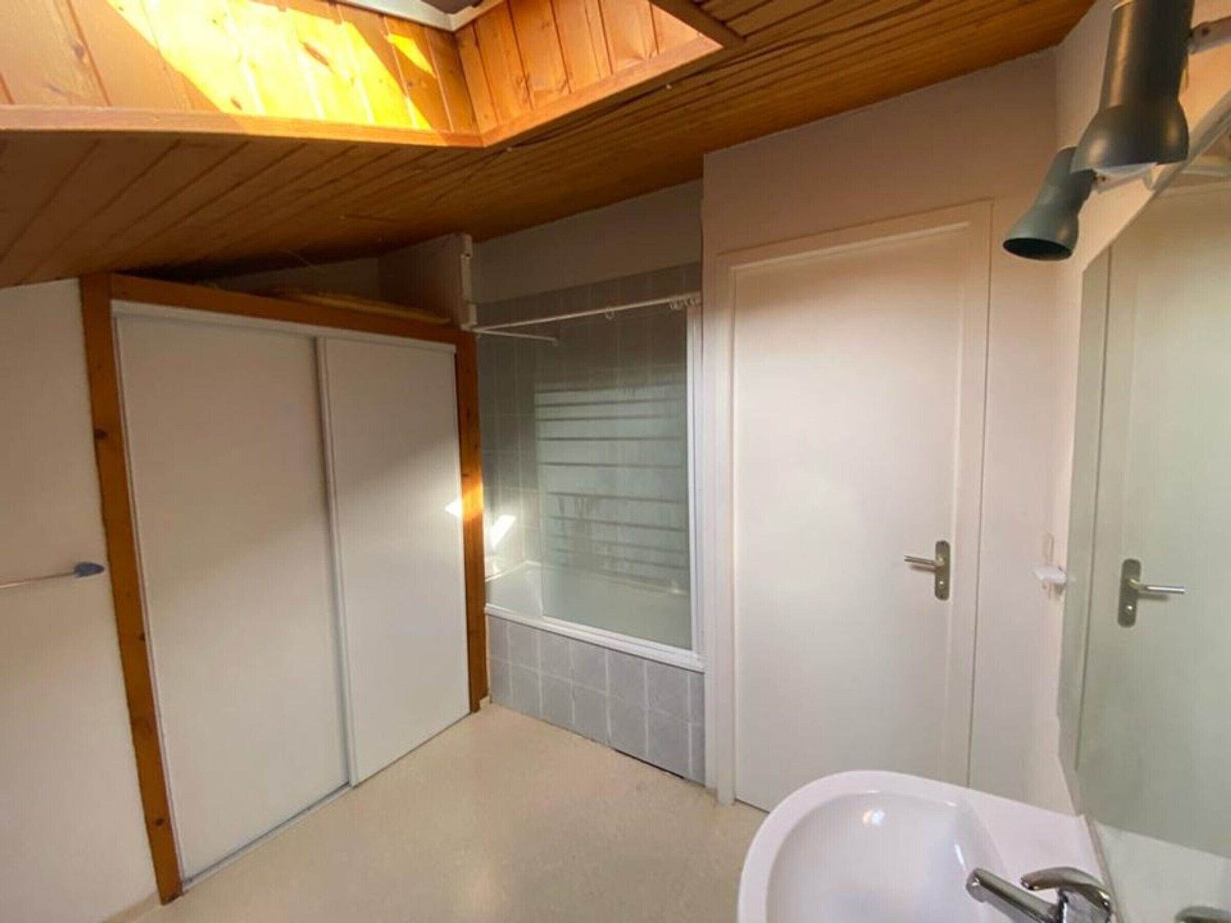 A bathroom with a sink, mirror, and shower.