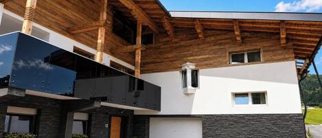 Ein modernes Gebäude mit Holzdach, Garage und einer Fassade aus Stein.