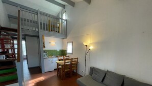 A spacious living area with a staircase leading to an upper level, a kitchen, and a seating area with a sofa and table. - Charming house near the port with parking and pets allowed (Capbreton)