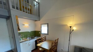 A compact kitchen with a dining table, chairs, a sink, and a staircase leading to an upper level. - Charming house near the port with parking and pets allowed (Capbreton)