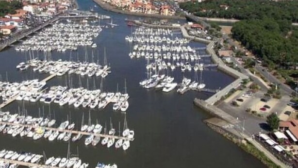 An aerial view of a marina with numerous boats docked, surrounded by buildings and greenery. - Charming house near the port with parking and pets allowed (Capbreton)