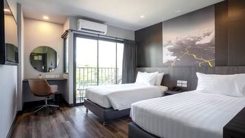 Una habitación de hotel moderna con dos camas, un escritorio, una silla, un ventanal grande y un aire acondicionado instalado en la pared.
