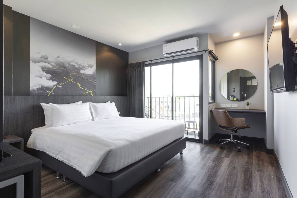 Ein modernes Hotelzimmer mit einem großen Bett, einem Schreibtisch, einem Stuhl und einem Balkon mit Blick.