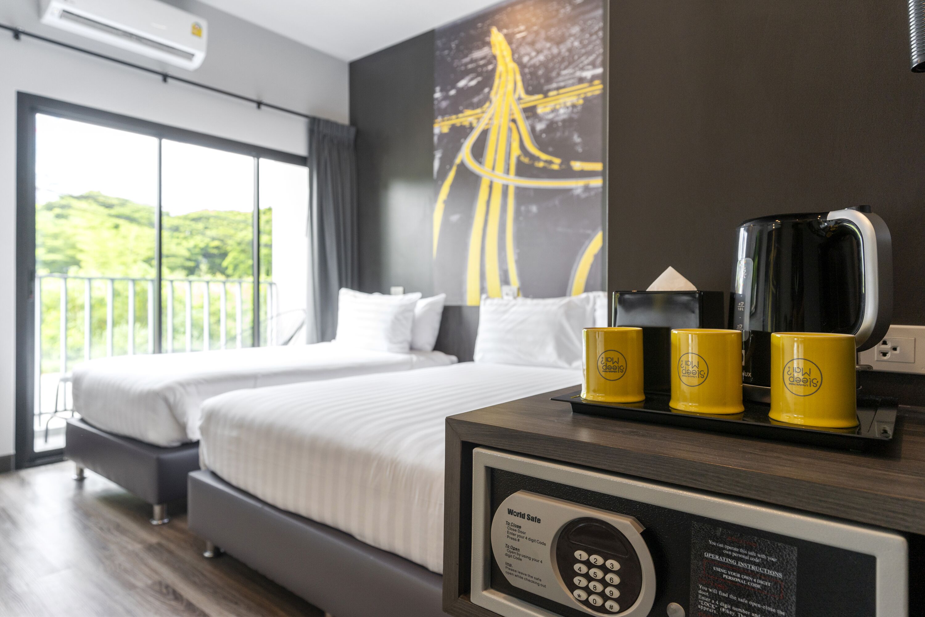 A hotel room with a large bed, a coffee maker, and a framed device on the nightstand.