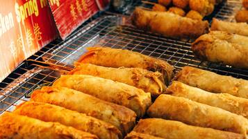 A variety of fried foods displayed on a grill, including spring rolls and other snacks.