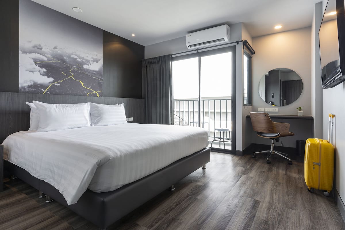 Ein modernes Hotelzimmer mit einem großen Bett, einem Schreibtisch, einem Stuhl und einem Koffer.