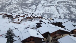Ein verschneites Dorf mit Holzhäusern und einer Bergkulisse.