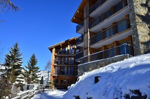 Un immeuble à plusieurs étages doté de balcons, d’une façade en bois et de détails en pierre.