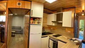 A compact kitchen with a built-in stove, a refrigerator, and a dining area with a table set for two. - Cerdanya Family House (Font Romeu - Odeillo)