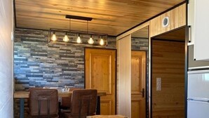 A compact kitchen with a wooden countertop, a dining area with two chairs, and a stone backsplash. - Cerdanya Family House (Font Romeu - Odeillo)