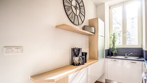 Een moderne keuken met een houten aanrecht, een koffiezetapparaat, een klok en een raam met uitzicht op gebouwen.
