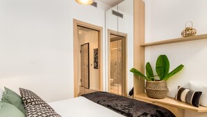 Een moderne slaapkamer met een bed, een nachtkastje, een plant en een kledingkast.