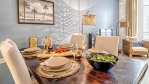 Een eethoek met een houten tafel gedekt voor vier personen, inclusief borden, glazen en een saladeschaal.