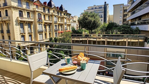 A balcony with a table set for a meal, overlooking a cityscape with historic buildings.
