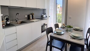 A modern kitchen with a dining area, featuring a sink, stove, and dining table set for four.