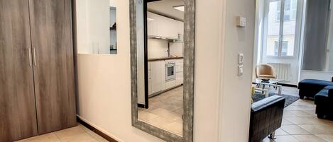 A modern kitchen with white cabinets and a large mirror.
