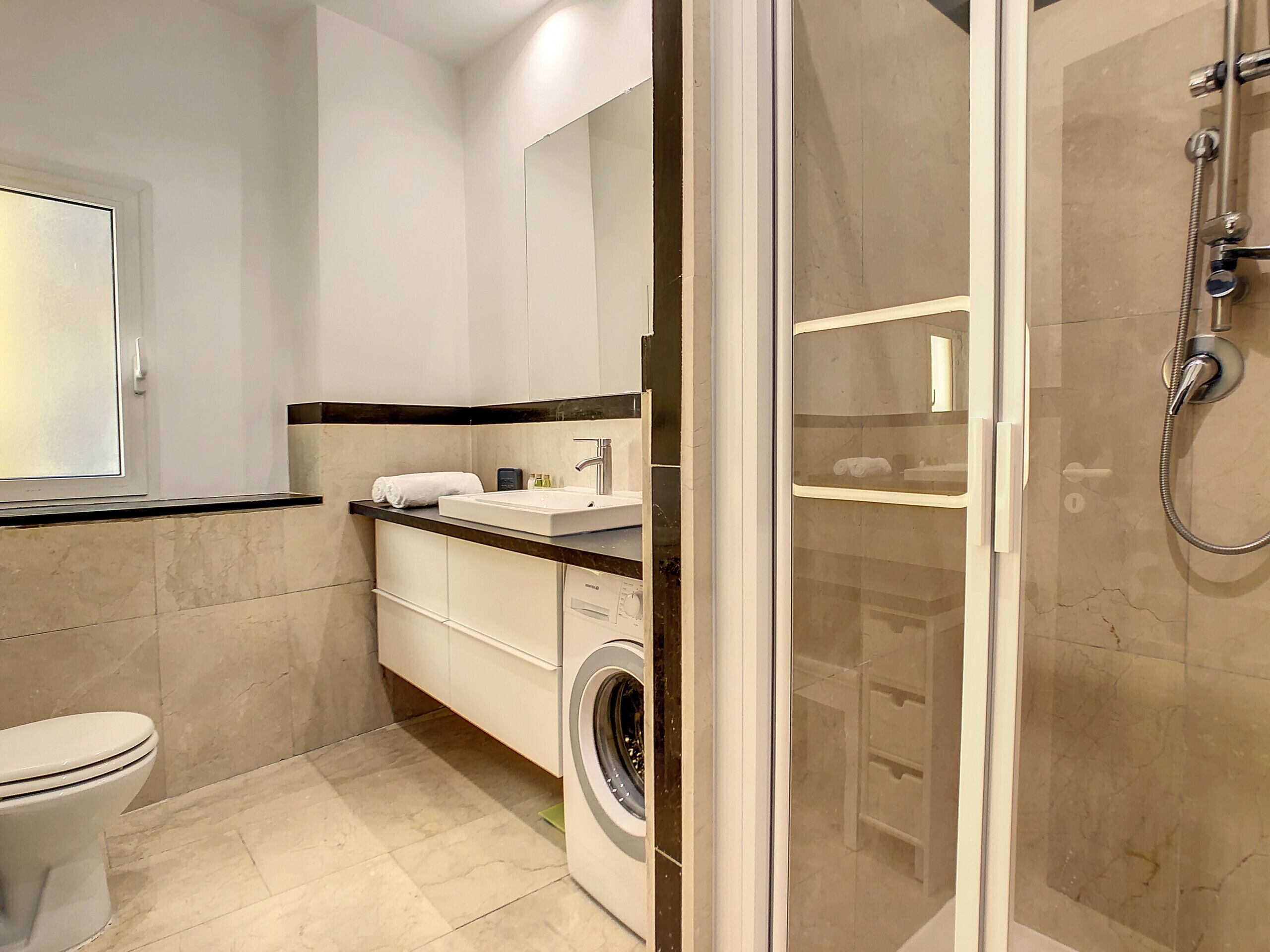 A modern bathroom with a toilet, sink, mirror, and glass-enclosed shower.
