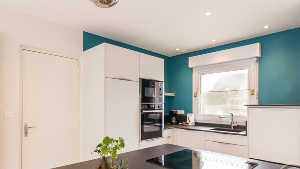 A modern kitchen with white cabinets, a black countertop, and a window with a view.