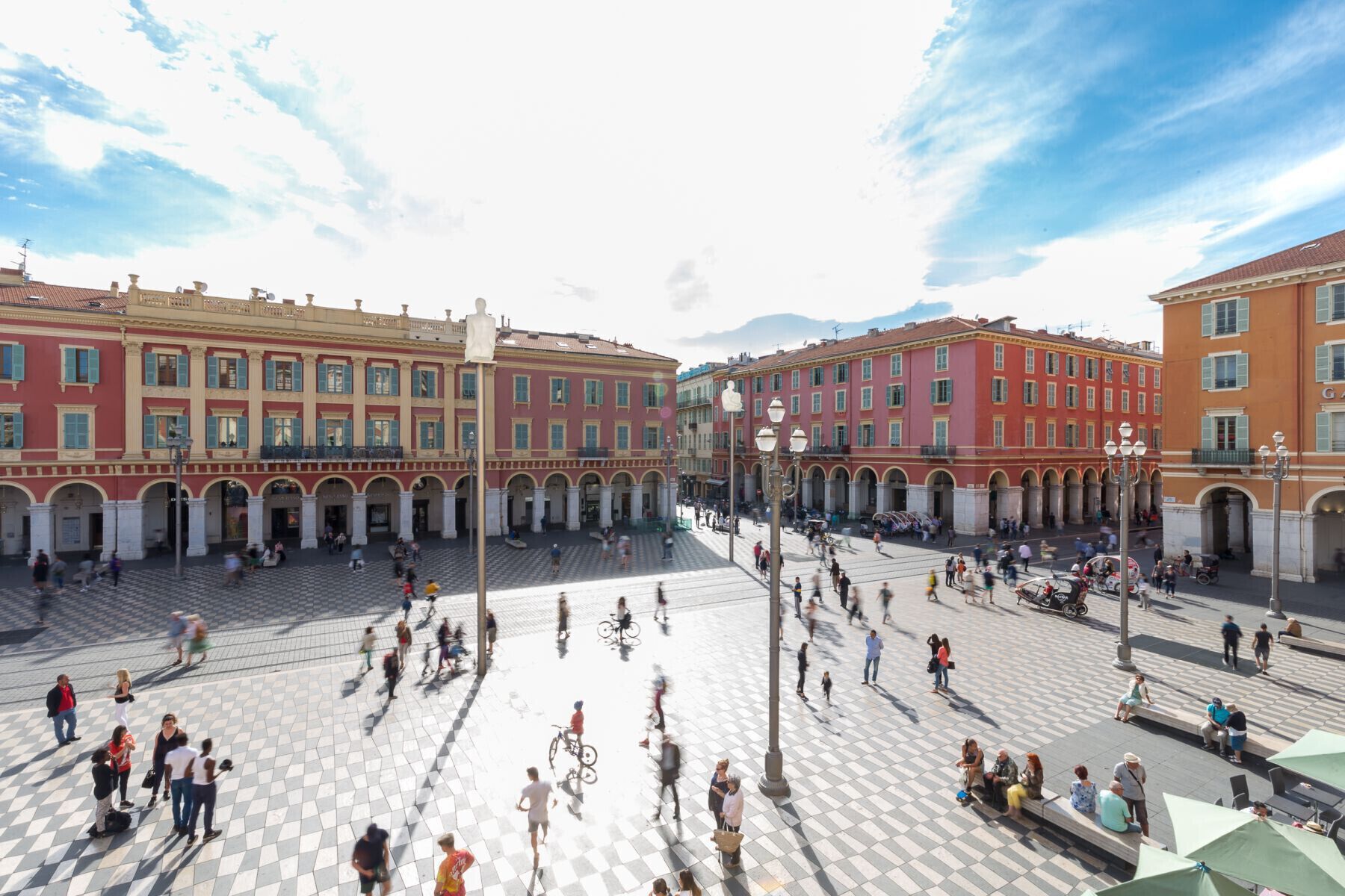 A spacious public square with historical buildings, a central fountain, and a tiled pavement.