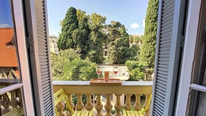A balcony with yellow chairs and a table, overlooking a garden with trees and a building in the background. - N&J -  ANGEL'S BAY - Central - Close sea (Niza)