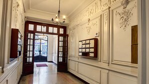 Un vaste hall d’entrée agrémenté d’un lustre, de décorations murales raffinées et d’un meuble en bois doté de tiroirs.