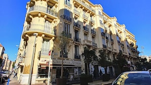 Un immeuble à plusieurs étages de style architectural classique, doté de balcons et d’un commerce situé au rez-de-chaussée.