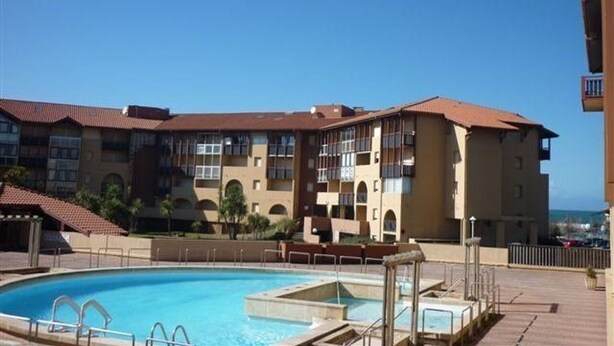 A hotel with a swimming pool, multiple balconies, and a view of the ocean.