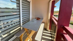A balcony with a table and bench, a sliding door, and a view of the water and buildings.