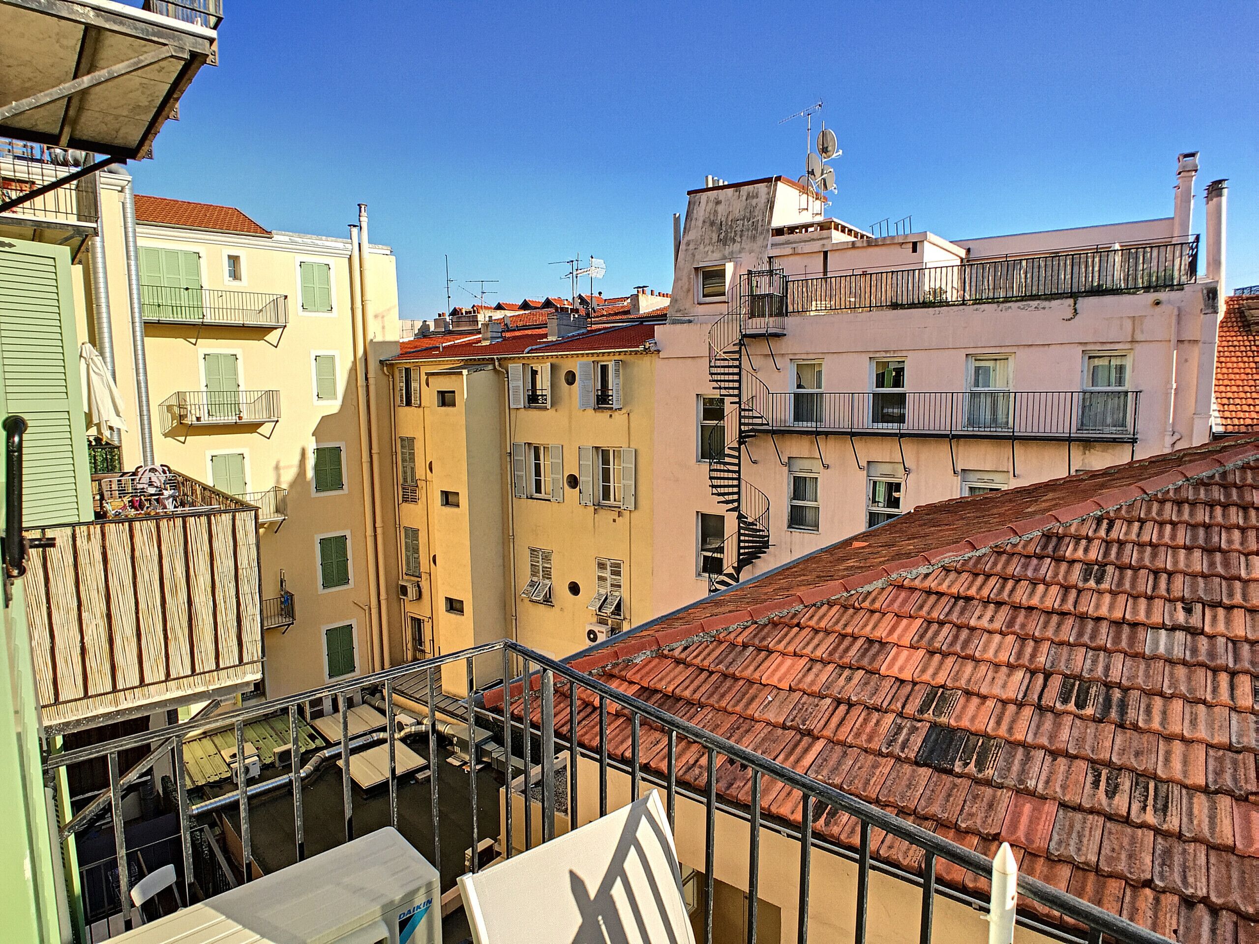A multi-story building with balconies, a visible staircase, and a red-tiled roof.