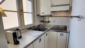 Een kleine keuken met een raam, een spoelbak en een koffiezetapparaat.