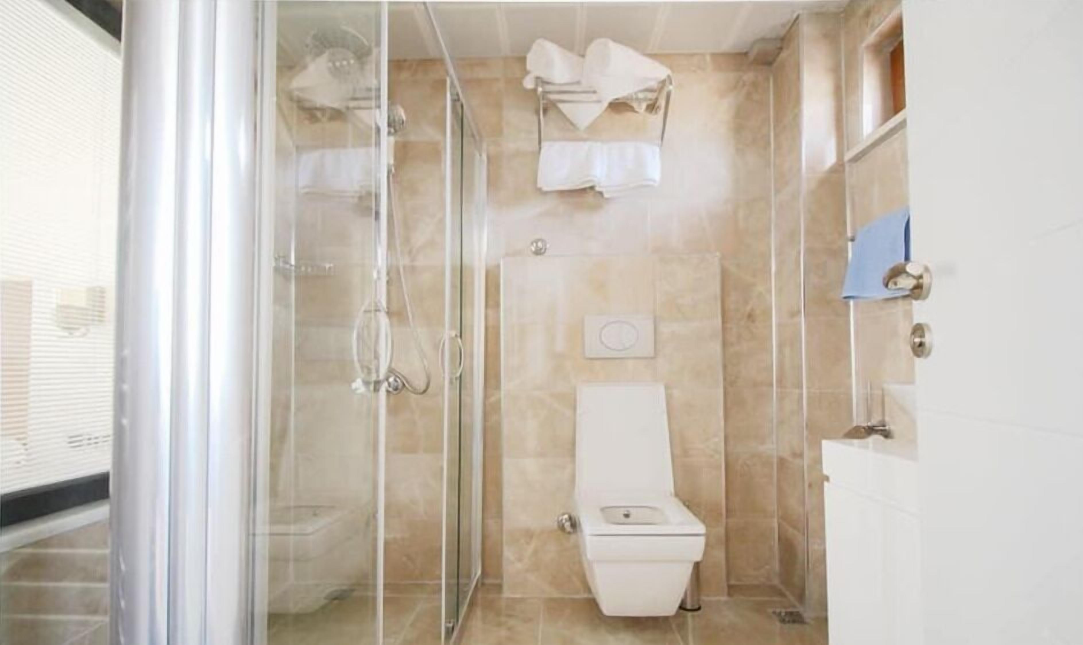 A bathroom with a glass-enclosed shower, a toilet, and a sink.