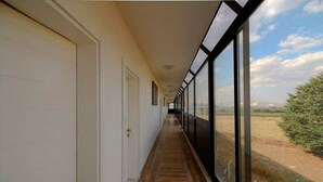 A corridor with a wooden floor, white doors, and large windows offering a view of the countryside. - Green Garden House Hotel&Spa (Tefenni)
