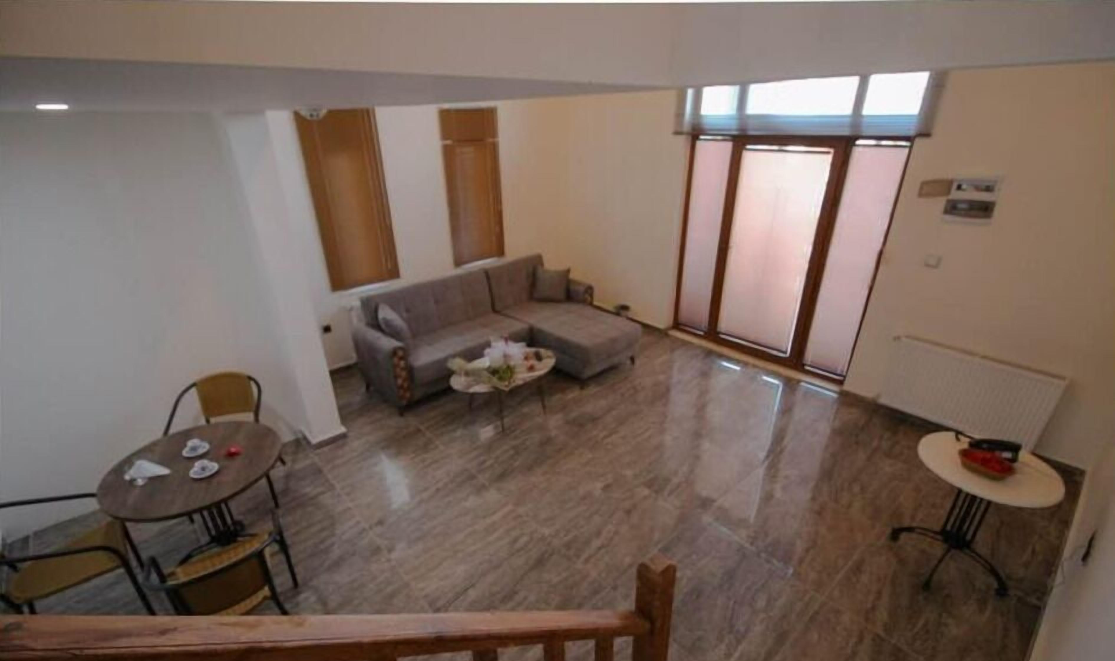 A spacious living area with a sofa, a small round table, and a dining table with chairs.