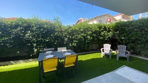 A patio with a table and chairs, surrounded by a well-maintained lawn and a hedge. - Garden-Level Apartment 100m from Beach with Parking & Terrace (Capbreton)
