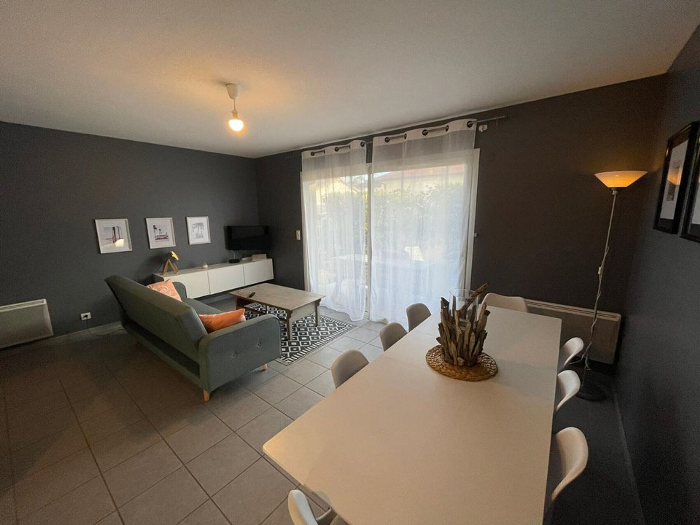 Een moderne woonkamer met een bank, een eettafel en een televisie.
