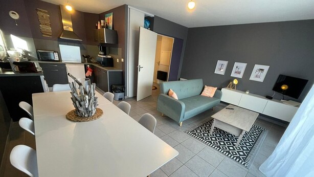 A modern living space with a dining area, kitchenette, and seating area. - Garden-Level Apartment 100m from Beach with Parking & Terrace (Capbreton)
