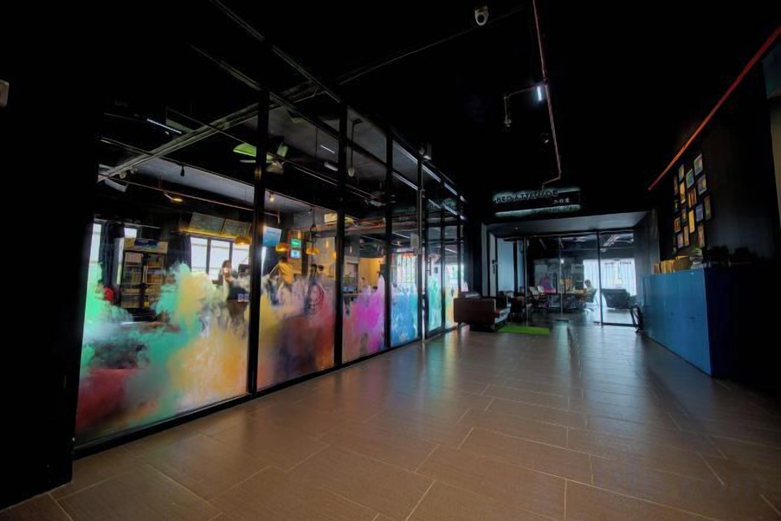 Interior modern amb partitions de vidre, una escala a la vista i una zona ben il·luminada amb un rètol.