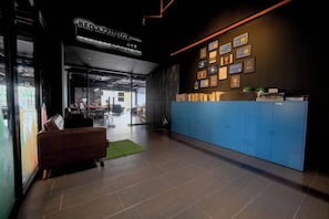 A reception area with a blue counter, framed pictures on the wall, and a sign above the counter. - Bed Attitude Hostel Cenang (Langkawi)