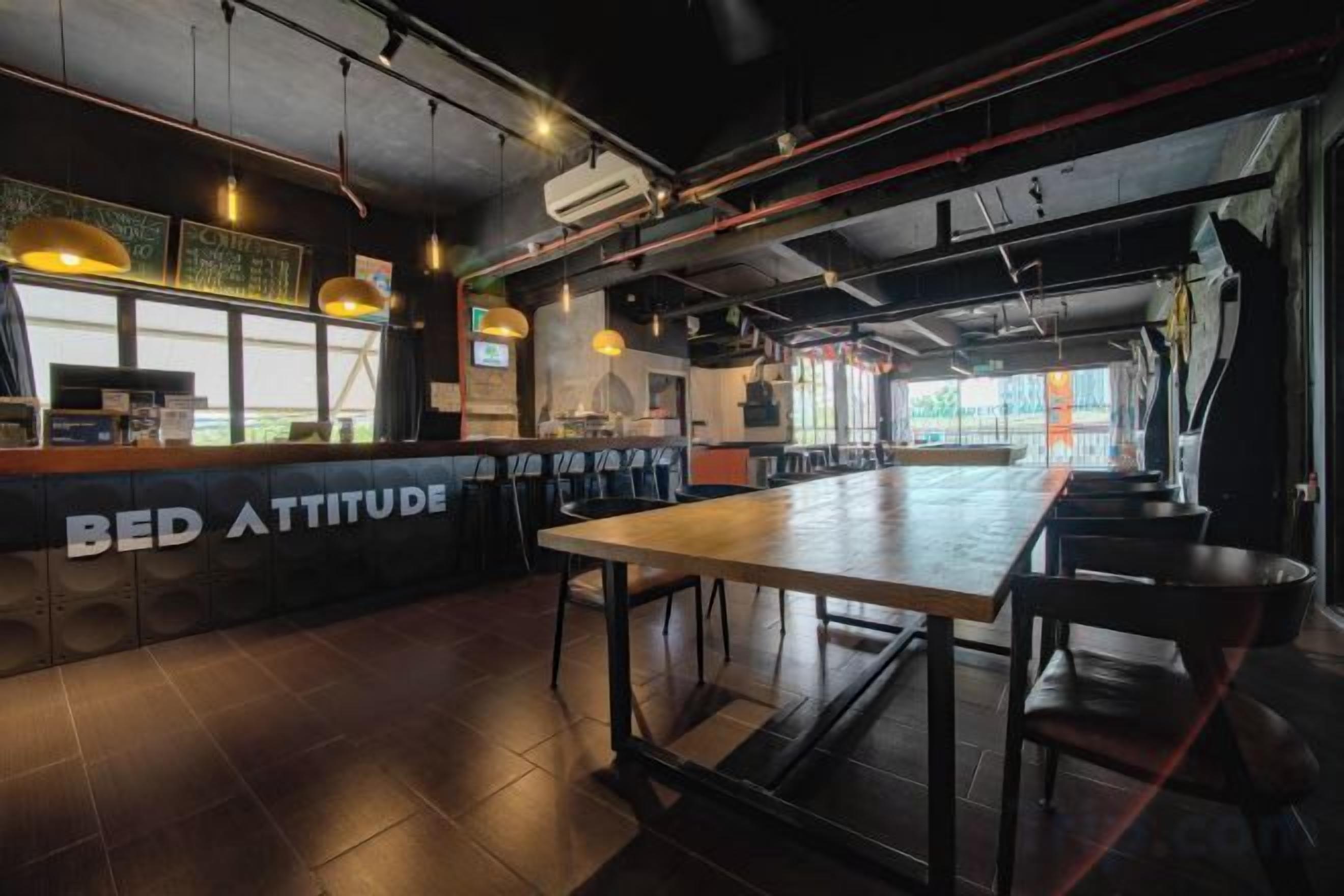 Un espace bar moderne doté d’un long comptoir, de sièges et de conduits apparents.