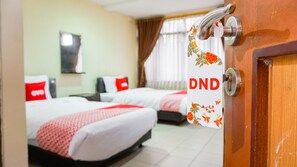A hotel room with two beds, a wooden door, and a window with curtains. - OYO 1739 Tekmira Residence Sudirman Syariah (Bandung)