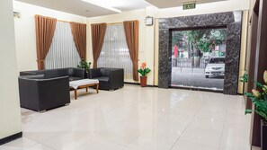 A reception area with a sofa, a small table, and a potted plant. - OYO 1739 Tekmira Residence Sudirman Syariah (Bandung)