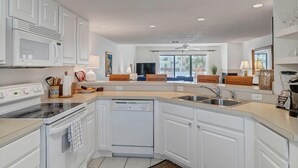 Una cocina moderna con armarios blancos, lavavajillas, estufa y pileta.