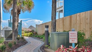 Un sendero conduce a un edificio con el letrero 'PRIVATE ACCESS RESIDENTS ONLY', rodeado de zonas ajardinadas con diversas plantas.