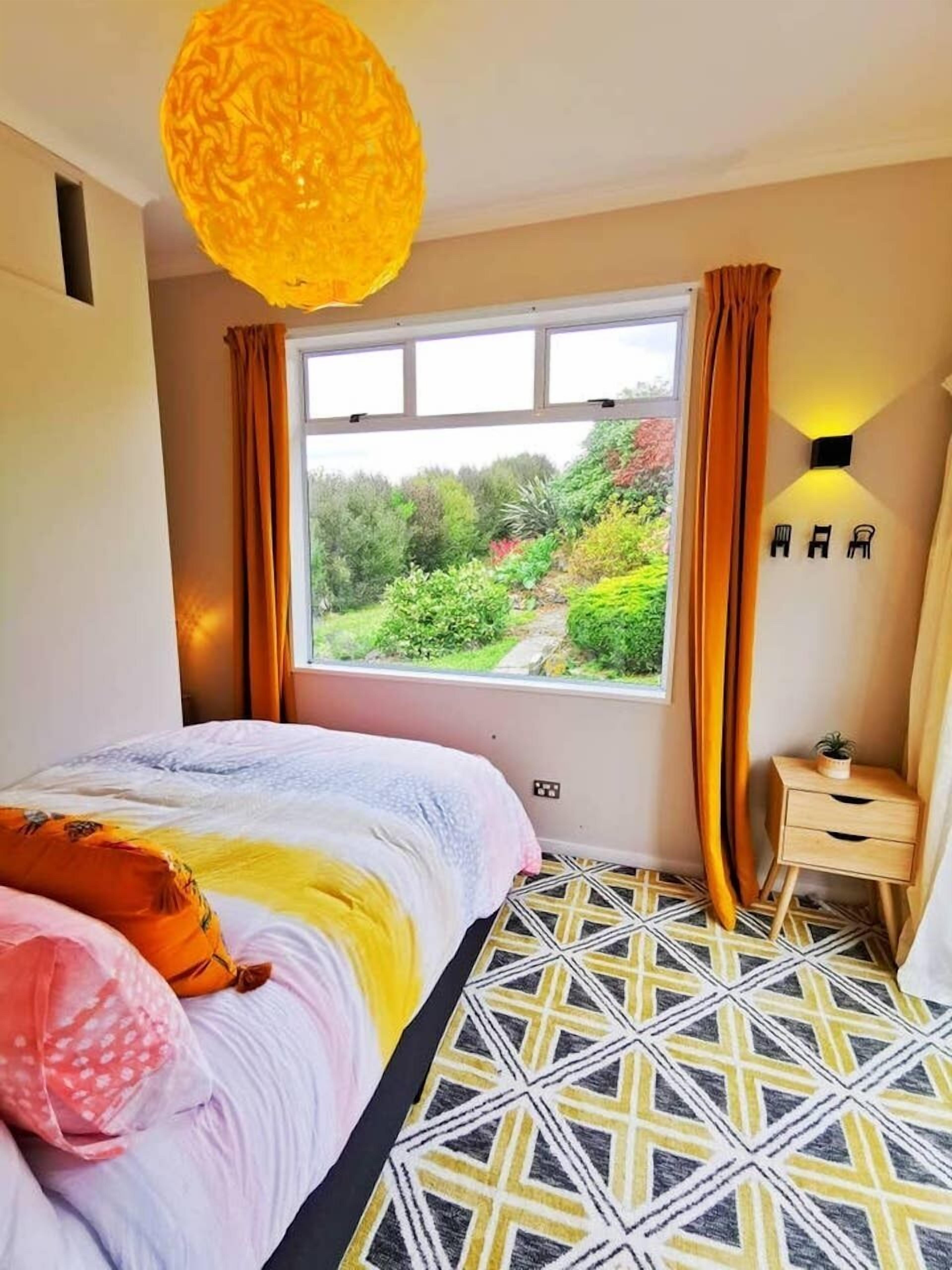 Een slaapkamer met een groot raam, een kamer met patroon en een bed met kussens.