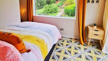 Een slaapkamer met een groot raam, een kamer met patroon en een bed met kussens.