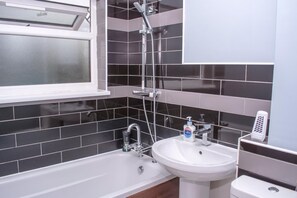 Tina con regadera, toallas, papel de baño 