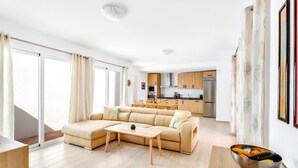A modern living room with a beige sectional sofa, a wooden coffee table, and a kitchen in the background. - Villa Chispita (Fuengirola)
