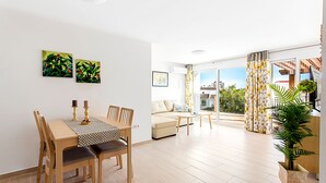 A spacious living area with a dining table, chairs, a sofa, and a large window with curtains. - Villa Chispita (Fuengirola)